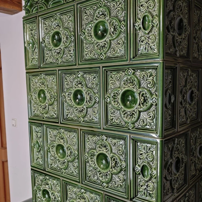 Piec kaflowy w głębokiej zieleni ze zdobieniami